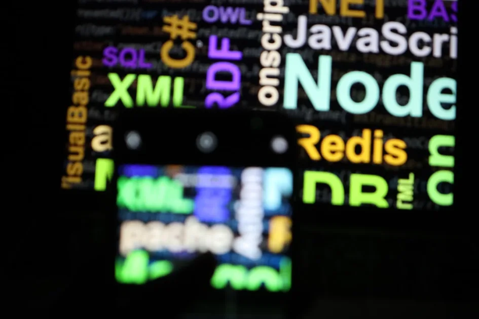 A smartphone screen displaying colorful programming language names against a dark background